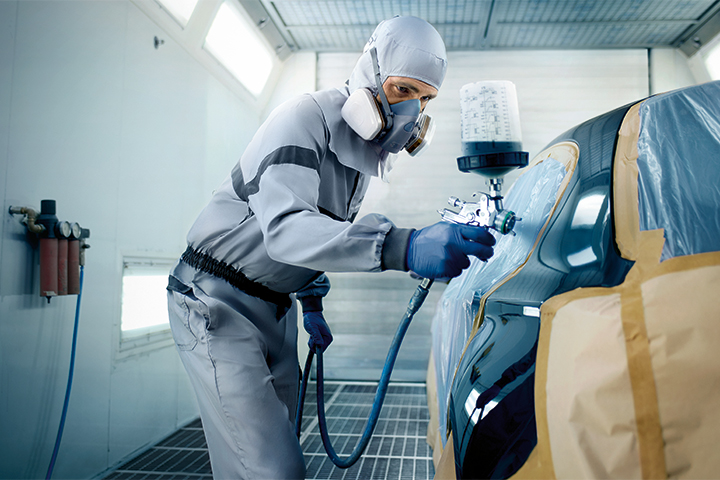 A technician in a Collision Repair Facility positioning a BMW for bodywork